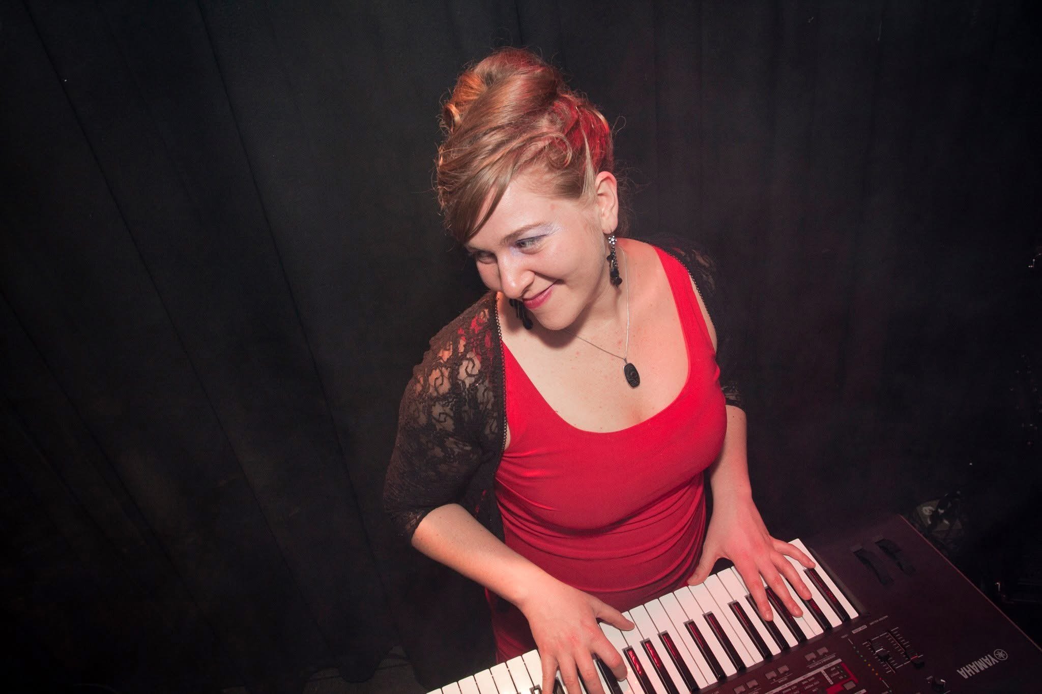 Suzanne Gay at the piano in a red dress